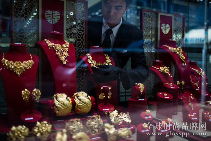 在位于香港旺角的一间门店里，一名周大福的工作人员正在整理橱窗内的 24K 黄金首饰。图片来源：Lam Yik Fei /《纽约时报》